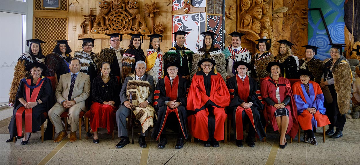 A picture of University graduates wearing kaakahu and academic gowns.